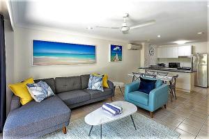 a living room with a couch and a table and a kitchen at Sunset Waters 10 & Free Buggy - Hamilton Island in Hamilton Island