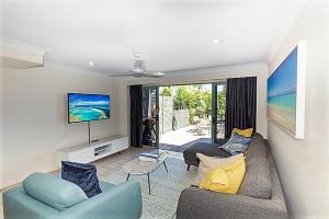 a living room with a couch and a tv at Sunset Waters 10 & Free Buggy - Hamilton Island in Hamilton Island