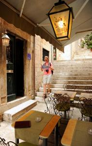 una mujer tomando una foto de un edificio con una cámara en Old Town Hostel en Dubrovnik