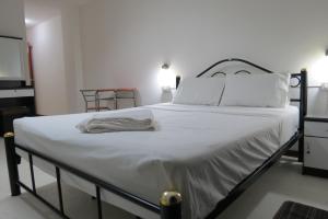 1 cama con sábanas blancas y almohadas en una habitación en Pizza Italy Restaurant and Guesthouse, en Pattaya central