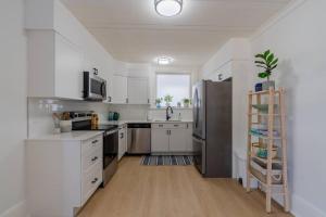 a kitchen with white cabinets and a stainless steel refrigerator at Charming 3BR Beach House with BBQ in Grand Bend in Grand Bend