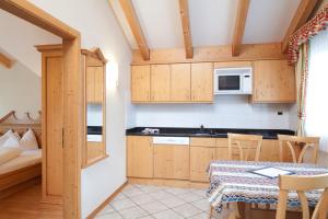 una cocina con armarios de madera y una mesa en una habitación en Ciasa Anteriol, en San Cassiano