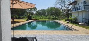 a swimming pool with an umbrella next to a house at Temuri Resort in Hambantota