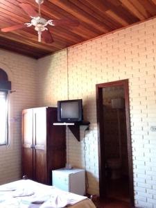 a room with a tv on a brick wall at Hotel Caracol in Canela