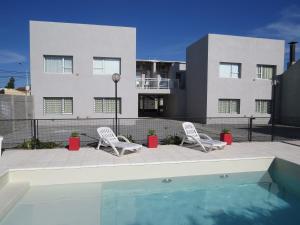 2 sillas y una piscina frente a un edificio en Roca Aparts & Suites Tandil en Tandil