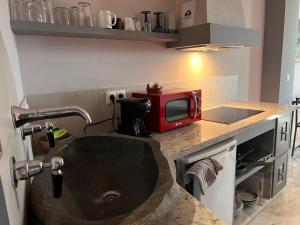 a kitchen with a sink and a red microwave at Estudio Amplio con Vistas Parciales al Mar in Maro +5 photos