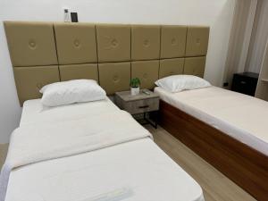 two twin beds in a room with a table at De Luxe in Talahib