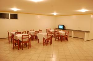 a dining room with tables and chairs and a tv at Minas Hotel Unidade Rodovia in Mariana