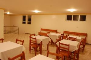 a dining room with white tables and wooden chairs at Minas Hotel Unidade Rodovia in Mariana