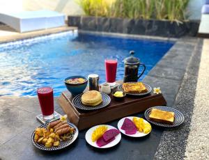 a table with food and drinks next to a pool at Stay Shark Villas Gili Air in Gili Islands
