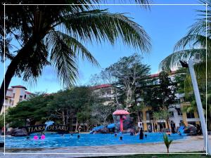 a pool at a resort with people in it at Tiara Desaru Residence Private Beach Bandar Penawar by Ucome Homestay in Bandar Penawar