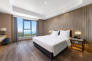 威海World Hotel Weihai International Bathing Beach Torch 8th Street Branch的一间带大床和大窗户的卧室