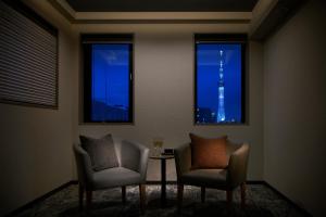 a room with two chairs and a table in front of two windows at Minn Asakusa Kappabashi in Tokyo