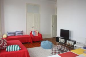 a living room with two red couches and a tv at Hostel 402 in Figueira da Foz