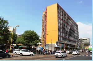 un edificio amarillo en una concurrida calle de la ciudad con coches en Apartamento Temporada Amazonas, en Manaus