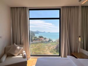 a bedroom with a large window with a view of the ocean at JD Elegance Lavanya Apartment in Pulau Tepur