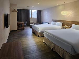 um quarto de hotel com duas camas e uma escrivaninha em CHECK inn Yilan LuoDong em Luodong mais 24 fotografias