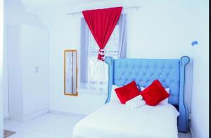 a bed with red pillows in a room with a window at 4 Callington guest house in Gqeberha