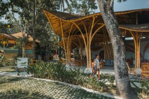 a man walking past a resort with a wooden pavilion at Tropik Resort Lombok in Selong Belanak