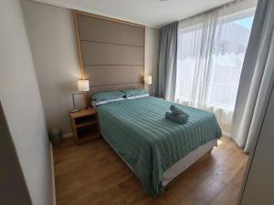 a bedroom with a bed with a teddy bear on it at Lagoon Beach Apartment 309 in Cape Town +10 photos