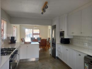 a kitchen with white cabinets and a dining room at Tog Wat Villa Marie in Hartenbos
