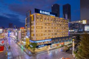un grande edificio in una città di notte di Bingo-威尔顿酒店-昆明火车站云纺商业城店 a Kunming