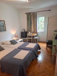 a bedroom with two beds and a table and a window at Apartments Mira in Cavtat