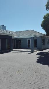 a blue building with a driveway in front of it at Garden Gate Guest House in Port Elizabeth