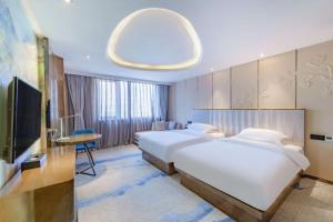 una camera d'albergo con due letti e una TV a schermo piatto di Bingo-威尔顿酒店-昆明火车站云纺商业城店 a Kunming