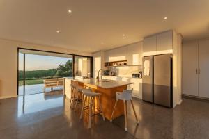 a kitchen with a island with stools and a refrigerator at Theunieskraal Nkwazi Ridge Estate in Zinkwazi Beach