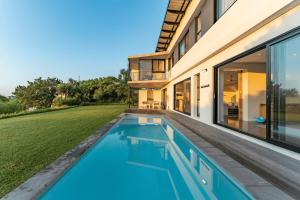a swimming pool in the backyard of a house at Theunieskraal Nkwazi Ridge Estate in Zinkwazi Beach