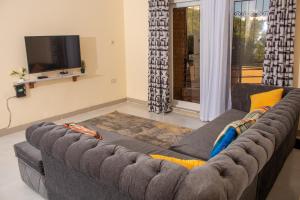 a grey couch in a living room with a tv at A Cozy 3 Bedroom Apartment With a Pool in Nyali in Mombasa