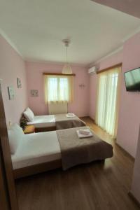 苏卡雷斯Villa Marina Tsoukalades的卧室设有两张床,拥有粉红色的墙壁和木地板