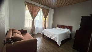 ein Schlafzimmer mit einem Bett und einer Couch und einem Fenster in der Unterkunft Carachula Guesthouse in Macas