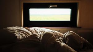 an unmade bed in a room with a window at La Tiny House de l'Ouchette in Brégy