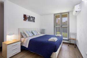 una camera da letto bianca con un letto blu e una finestra di Suite Strada Persa a Pavia
