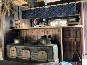 京都cafe & guesthouse 魚ヶ淵的厨房配有炉灶和带锅碗瓢盆的架子。 更多17张照片