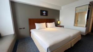 a bedroom with a large white bed with a window at Star Hotel Chiang Mai in Chiang Mai