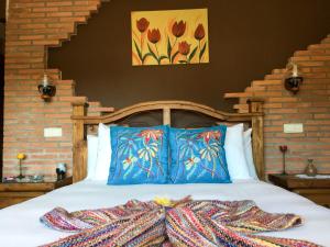 a bedroom with a bed with blue pillows and colorful blankets at La Guarida del Oso in Candeleda +18 photos