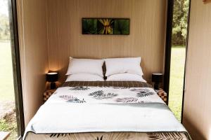 a bed in a room with a large window at Farmhouse 1 at Coffs by Tiny Away in Boambee