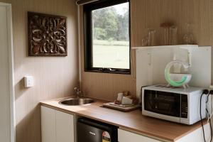 a kitchen with a microwave and a sink and a window at Farmhouse 1 at Coffs by Tiny Away in Boambee