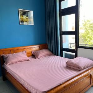 een bed met roze kussens in een kamer met een raam bij Nhà Nghỉ FAMI in Ho Chi Minh-stad +9 foto's