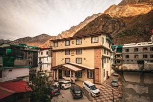 巴德里纳特New Hotel Snow Crest的山前停车场内有车辆的建筑物