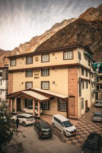 巴德里纳特New Hotel Snow Crest的一座大楼，停车场里停满了汽车