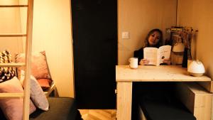 a woman sitting at a table reading a book at La Tiny House de l'Ouchette in Brégy