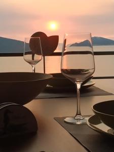 two glasses of wine sitting on a table with the sunset at Marmari megali ammos oasis studio's in Ayía Marína