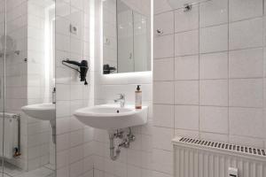 ein weißes Badezimmer mit zwei Waschbecken und einem Spiegel in der Unterkunft ROTH Apartments Solingen-HBF in Solingen