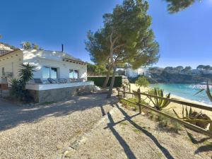 ein weißes Haus mit einem Zaun am Wasser in der Unterkunft Almadrague Villa in Roses