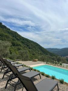 a row of lounge chairs next to a swimming pool at Tipì Arya in Chiusanico +12 photos
