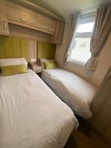 two beds in a small room with a window at Sunflower 62 Braunton in Ashford